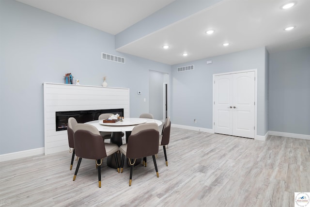 dining area with visible vents, recessed lighting, light wood-type flooring, and a glass covered fireplace