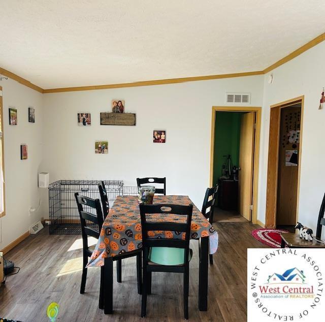214 SE State St, Milan, MO 63556 - dining room with baseboards, visible vents, crown molding, and dark wood-type flooring