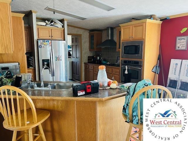 214 SE State St, Milan, MO 63556 - kitchen with wall chimney range hood, a breakfast bar area, a sink, appliances with stainless steel finishes, and a peninsula