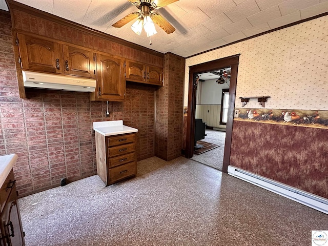 kitchen with under cabinet range hood, a ceiling fan, crown molding, light countertops, and a baseboard radiator