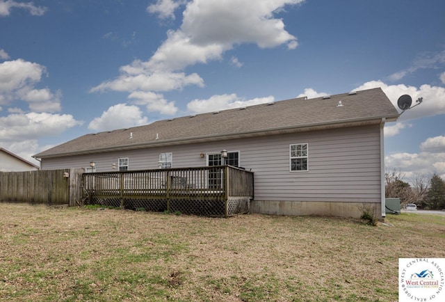 rear view of house with a lawn, fence, and a deck