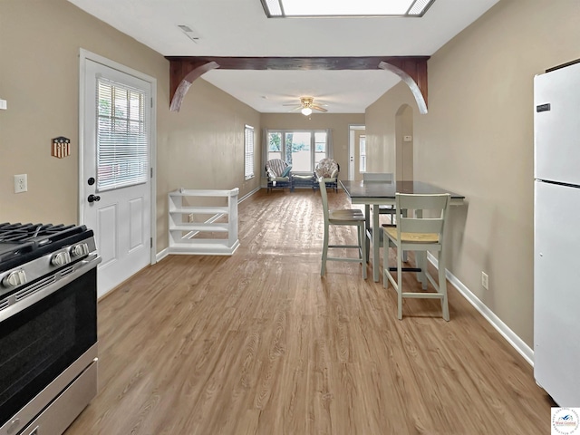 26684 Waterview Dr, Warsaw, MO 65355 - kitchen featuring stainless steel range with gas stovetop, freestanding refrigerator, arched walkways, light wood-style flooring, and a ceiling fan