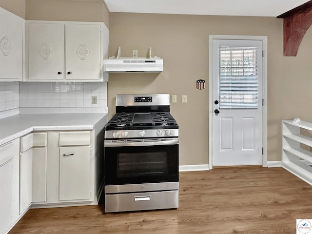 26684 Waterview Dr, Warsaw, MO 65355 - kitchen with stainless steel range with gas stovetop, under cabinet range hood, light countertops, white cabinetry, and backsplash