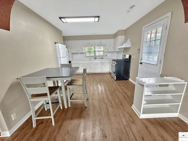 26684 Waterview Dr, Warsaw, MO 65355 - kitchen with gas range, freestanding refrigerator, light wood-type flooring, and white cabinets