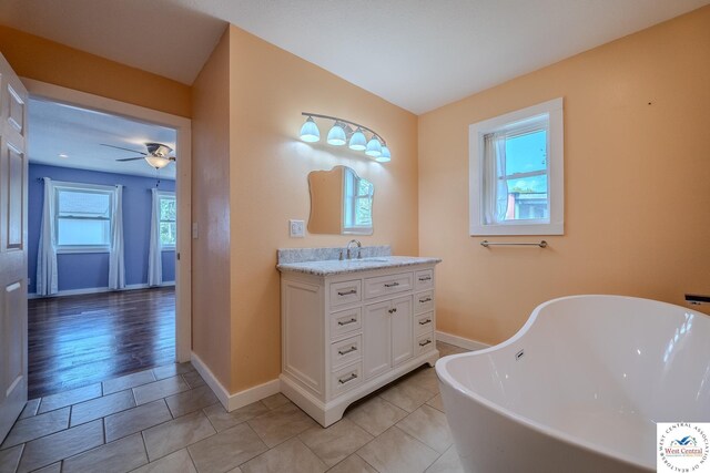 28848 Paradise Dr, Warsaw, MO 65355 - full bath featuring a freestanding bath, baseboards, a ceiling fan, and vanity