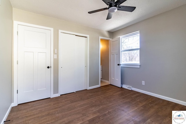 unfurnished bedroom featuring dark wood-style floors, ceiling fan, visible vents, baseboards, and a textured ceiling