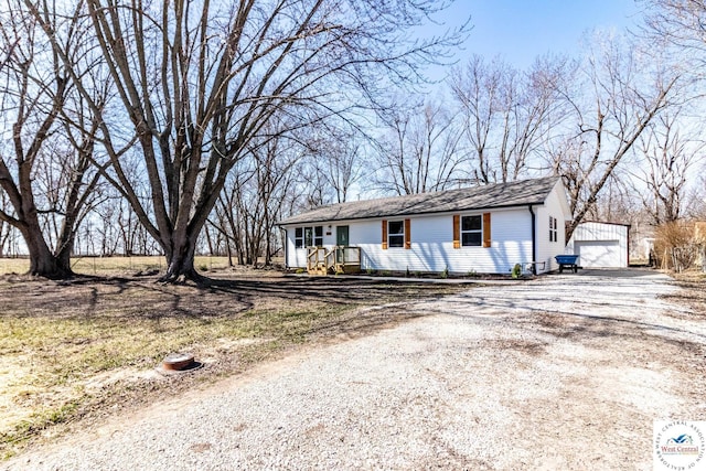 view of front of property featuring a garage, gravel driveway, and an outbuilding