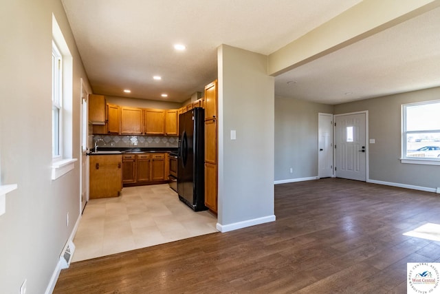 kitchen with decorative backsplash, freestanding refrigerator, dark countertops, baseboards, and open floor plan