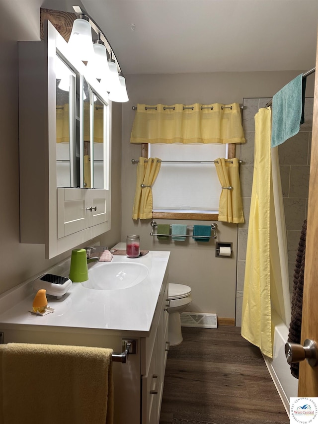 bathroom featuring shower / bath combo, visible vents, toilet, wood finished floors, and vanity