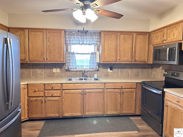 kitchen with dark wood finished floors, a ceiling fan, appliances with stainless steel finishes, and a sink