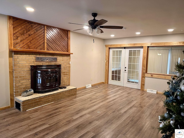 unfurnished living room with a ceiling fan, visible vents, baseboards, french doors, and wood finished floors