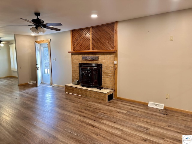 unfurnished living room featuring wood finished floors, visible vents, a ceiling fan, and baseboards