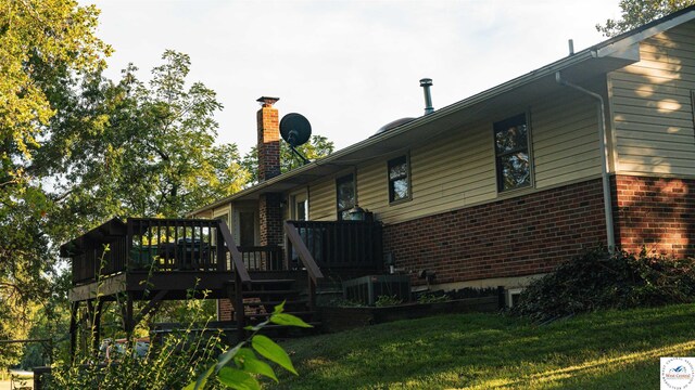 23111 Lange Rd, Cole Camp, MO 65325 - back of property featuring a deck, a chimney, a yard, central AC, and brick siding