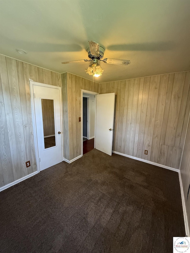 7801 Ozark Rd, Kansas City, MO 64129 - unfurnished bedroom featuring wooden walls, dark carpet, and ceiling fan