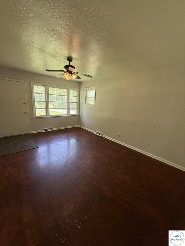 7801 Ozark Rd, Kansas City, MO 64129 - empty room featuring plenty of natural light, a ceiling fan, dark wood finished floors, and a textured ceiling