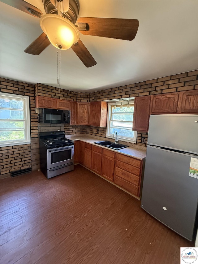 7801 Ozark Rd, Kansas City, MO 64129 - kitchen with appliances with stainless steel finishes, light countertops, brown cabinetry, dark wood-style flooring, and brick wall