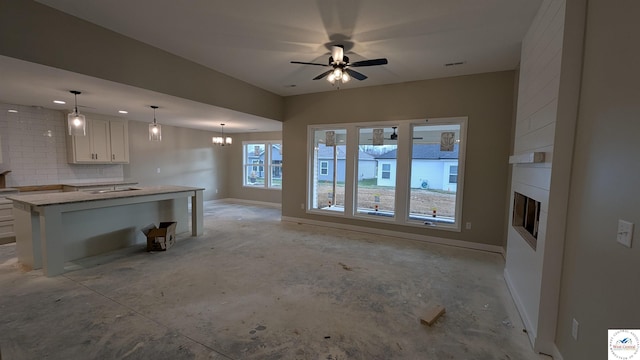 302 E Jamestown Dr, Clinton, MO 64735 - unfurnished living room with a large fireplace, unfinished concrete floors, a ceiling fan, and a chandelier