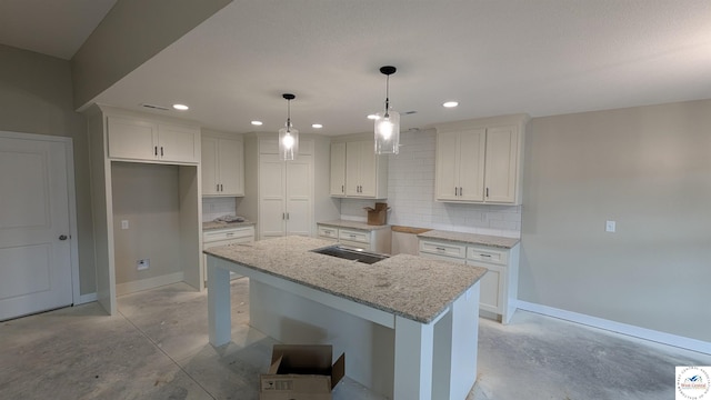 302 E Jamestown Dr, Clinton, MO 64735 - kitchen featuring concrete flooring, tasteful backsplash, white cabinets, an island with sink, and light stone counters