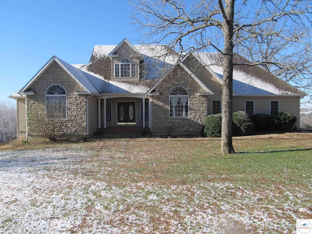 view of front of home with roof with shingles, a front yard, and stone siding