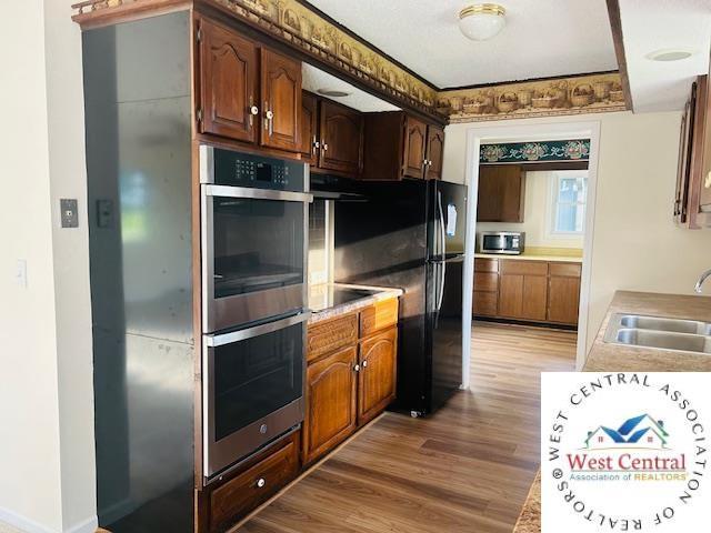 45869 E Hwy, Milan, MO 63556 - kitchen featuring stainless steel appliances, light wood-style flooring, light countertops, and ventilation hood