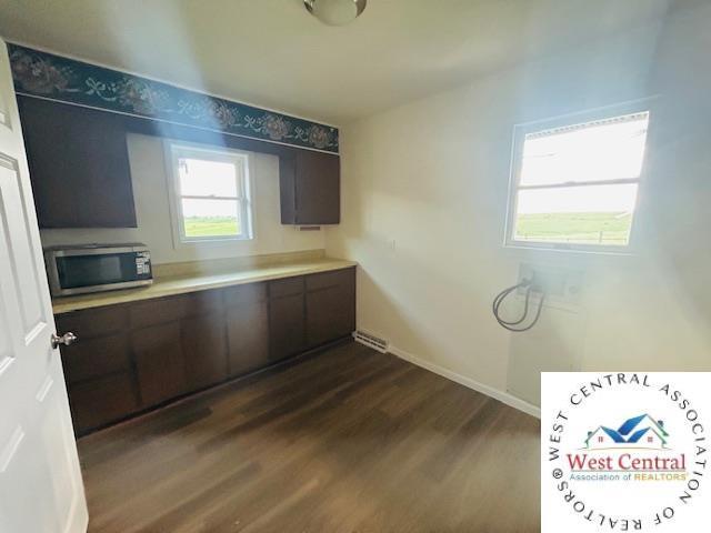 45869 E Hwy, Milan, MO 63556 - kitchen with stainless steel microwave, dark wood-style flooring, light countertops, and dark brown cabinets