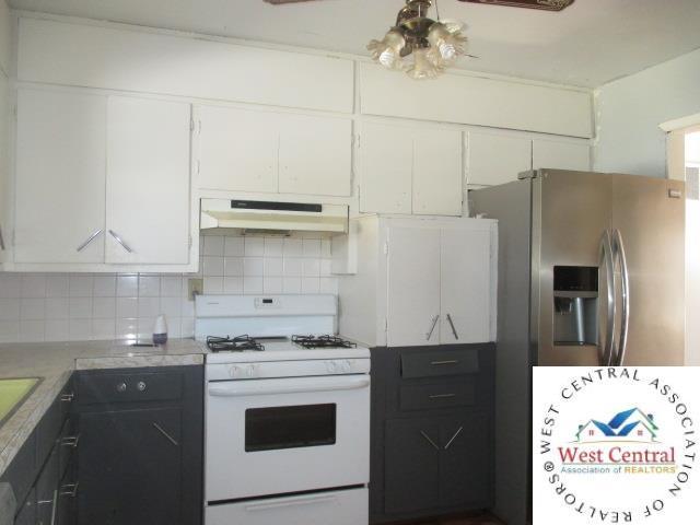 kitchen featuring white cabinets, light countertops, white range with gas stovetop, under cabinet range hood, and stainless steel fridge with ice dispenser