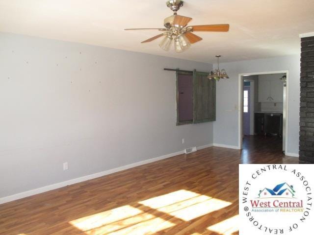 unfurnished room with a barn door, baseboards, wood finished floors, and ceiling fan with notable chandelier