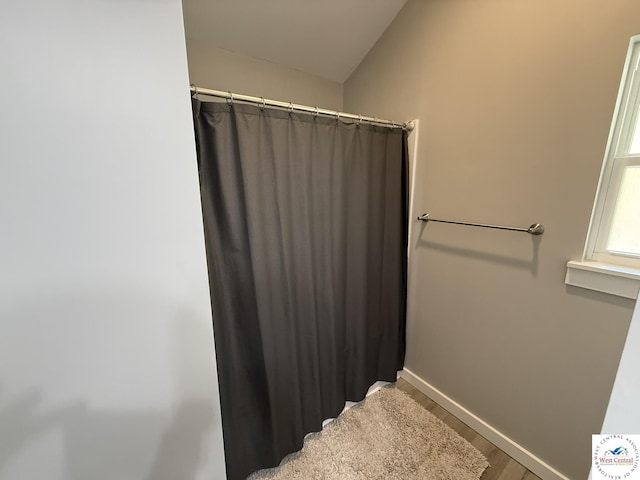 bathroom with wood finished floors, baseboards, and a shower with shower curtain