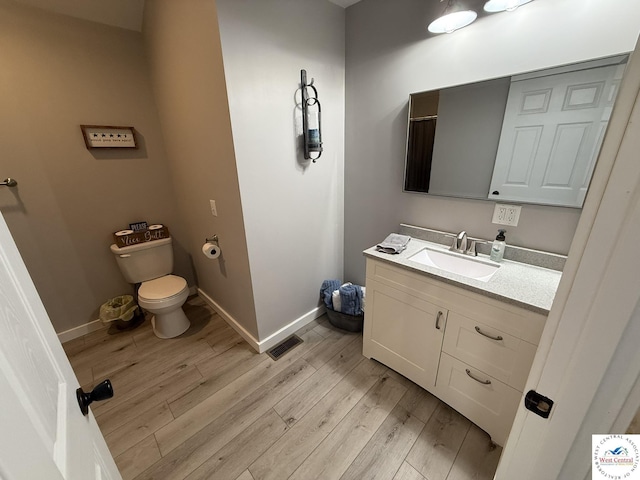 bathroom with wood finished floors, vanity, baseboards, and toilet