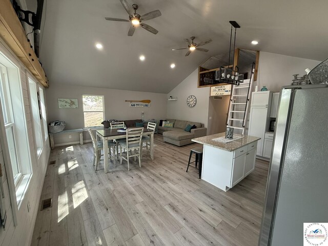 kitchen featuring freestanding refrigerator, ceiling fan, lofted ceiling, a center island, and white cabinetry