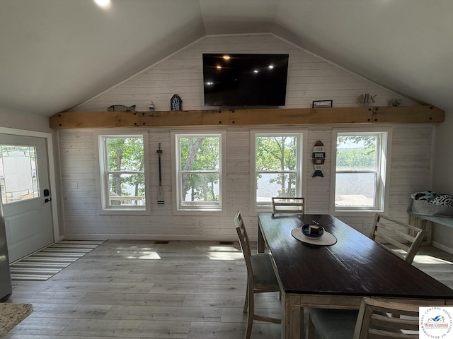 dining room featuring vaulted ceiling, wood walls, and wood-type flooring