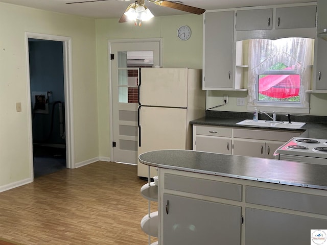 1511 Polk St, Warsaw, MO 65355 - kitchen with freestanding refrigerator, a sink, light wood-style floors, ceiling fan, and dark countertops