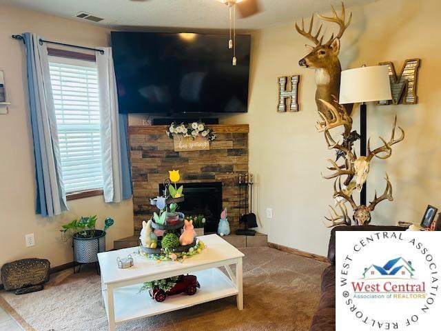 913 S Main St, Milan, MO 63556 - carpeted living area with visible vents, a stone fireplace, and baseboards