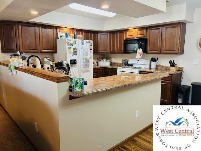 913 S Main St, Milan, MO 63556 - kitchen featuring light stone counters, a sink, dark wood-style floors, recessed lighting, and white appliances