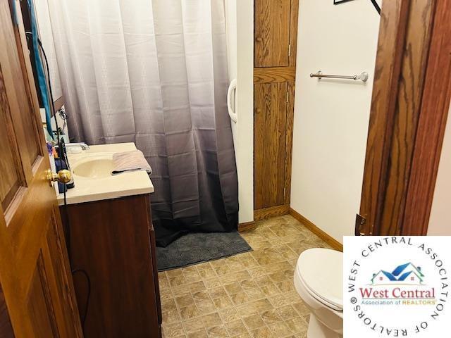 913 S Main St, Milan, MO 63556 - bathroom with baseboards, a shower with shower curtain, toilet, and vanity