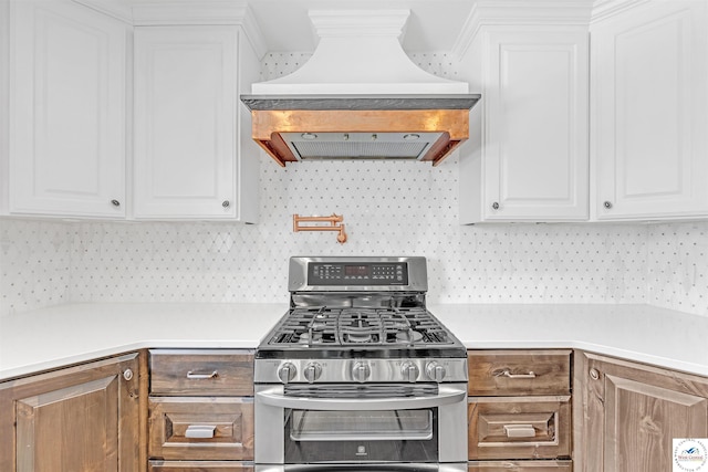 1715 Sycamore Dr, Sedalia, MO 65301 - kitchen featuring island range hood, white cabinetry, light countertops, and gas range