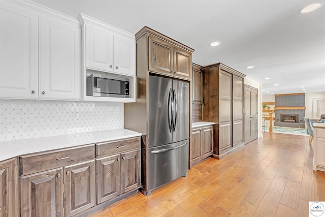 1715 Sycamore Dr, Sedalia, MO 65301 - kitchen featuring white cabinetry, stainless steel appliances, light countertops, open floor plan, and light wood finished floors
