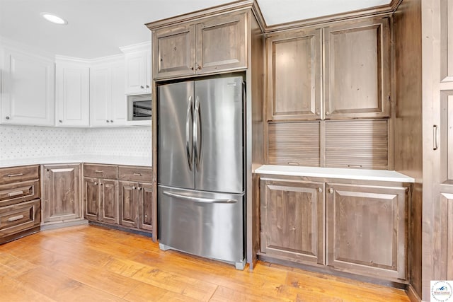 1715 Sycamore Dr, Sedalia, MO 65301 - kitchen with white cabinetry, light wood-type flooring, appliances with stainless steel finishes, and light countertops