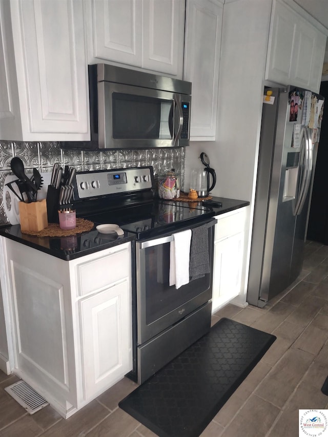 kitchen with wood finish floors, dark countertops, visible vents, and appliances with stainless steel finishes