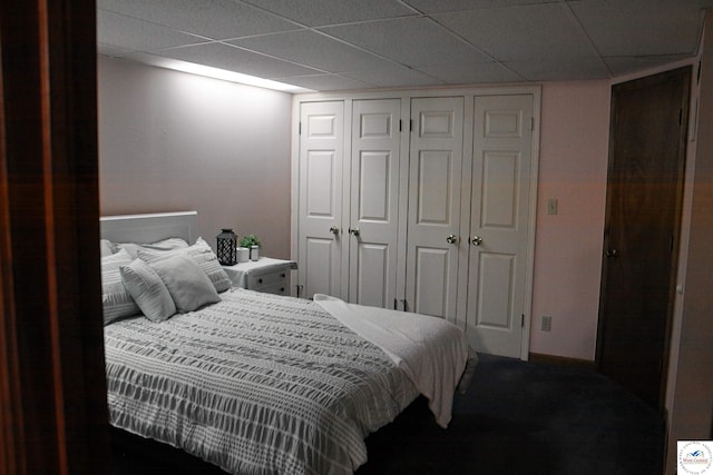 carpeted bedroom featuring a closet and a drop ceiling