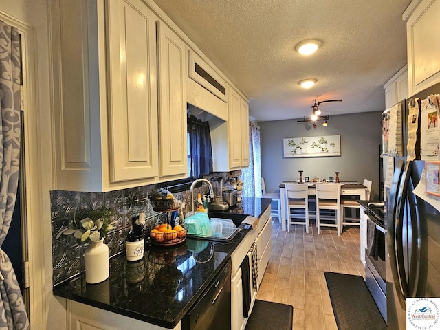 kitchen featuring a sink, stainless steel range with electric cooktop, light wood-style flooring, a textured ceiling, and freestanding refrigerator