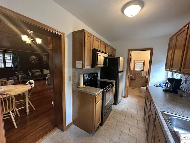 29193 Roundhouse Ave, Lincoln, MO 65338 - kitchen featuring black range with electric stovetop, freestanding refrigerator, backsplash, and brown cabinets
