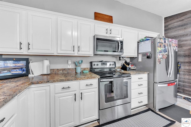 2510 Stephenson Ave, Sedalia, MO 65301 - kitchen with appliances with stainless steel finishes, white cabinetry, and wood walls