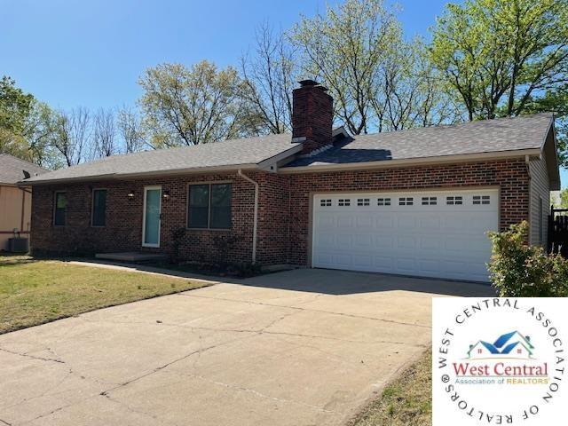 single story home with a chimney, brick siding, a front yard, concrete driveway, and an attached garage