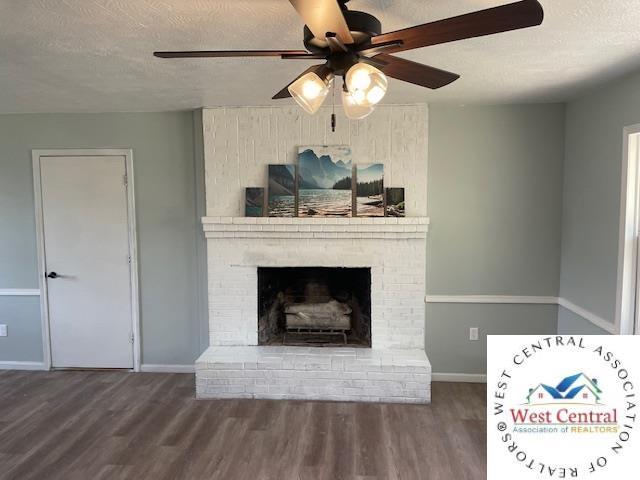 unfurnished living room featuring a textured ceiling, ceiling fan, baseboards, a fireplace, and wood finished floors
