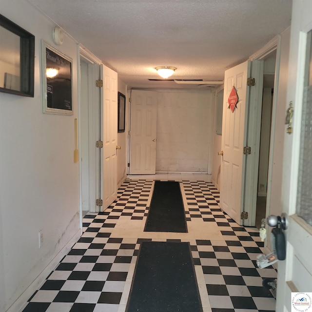 hall with tile patterned floors and a textured ceiling