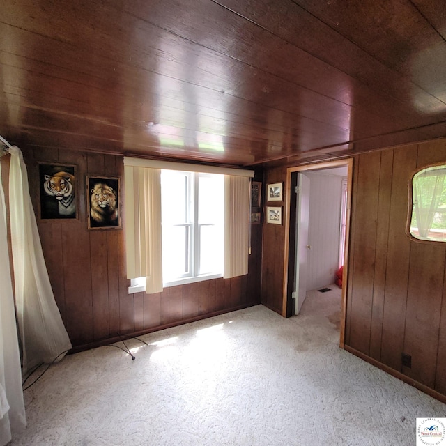 unfurnished room with wooden ceiling, wooden walls, and carpet floors
