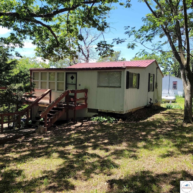 rear view of property featuring metal roof and a yard