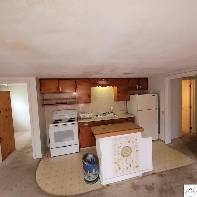 kitchen with white appliances, under cabinet range hood, a sink, and brown cabinets