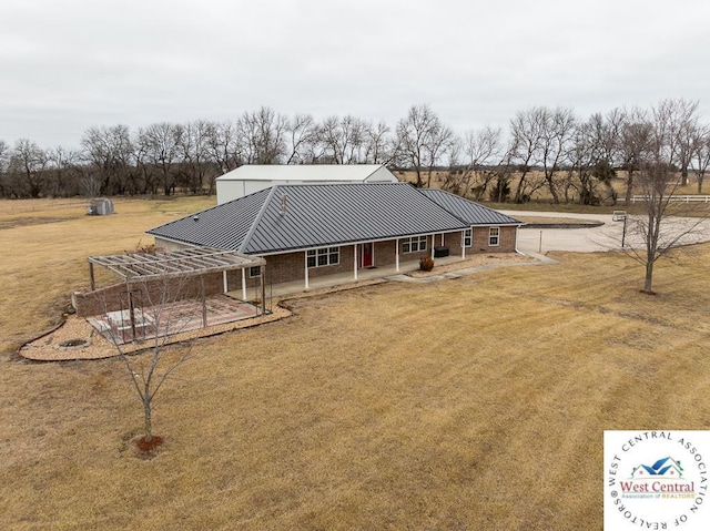 back of property featuring brick siding, a standing seam roof, metal roof, and a lawn